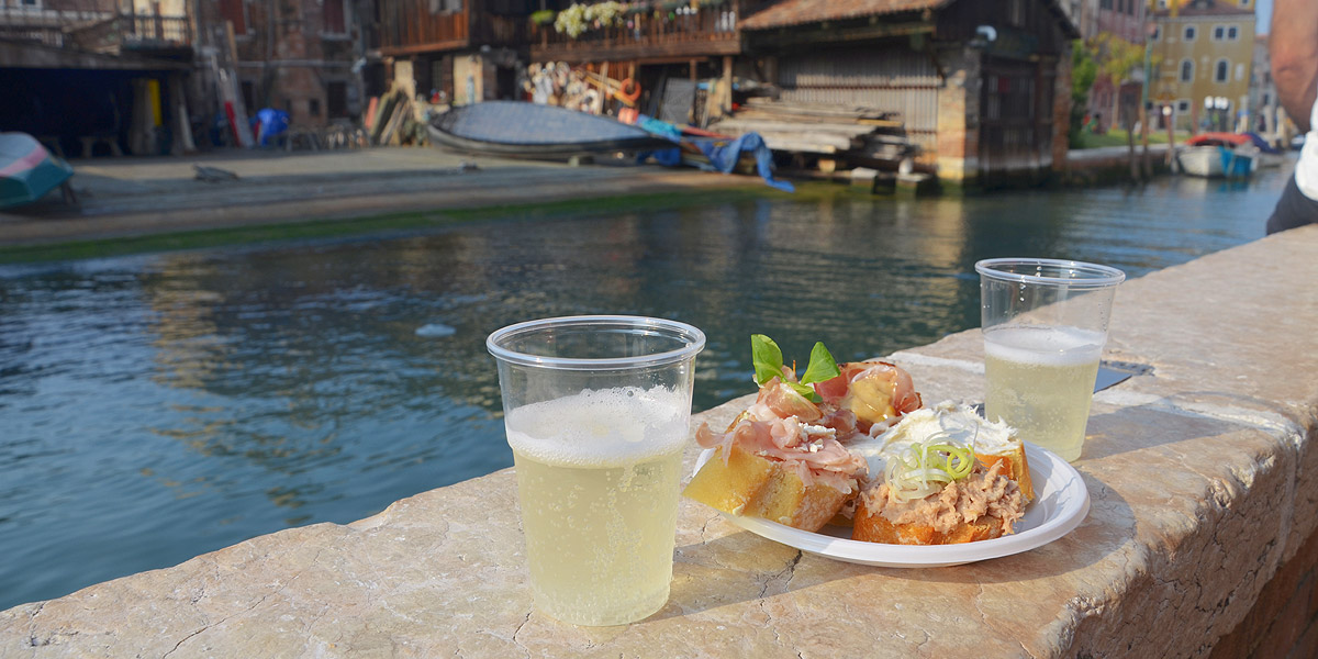 "Ombra" (ein Gläschen) an der Lagune von Venedig mit Prosecco und Cicchetti (Cicheti), Venedigs berühmte Appetithäppchen. Autor: Monika Ďuríčková (bearbeitet)